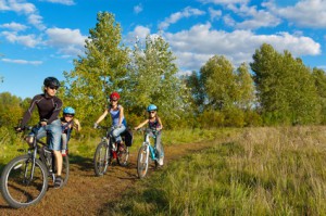 Family cycling outdoors. Happy parents with two kids on bikes
