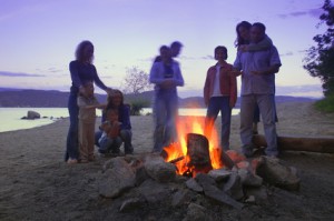 A Group Of Friends And Family Around A Bonfire On The Beach